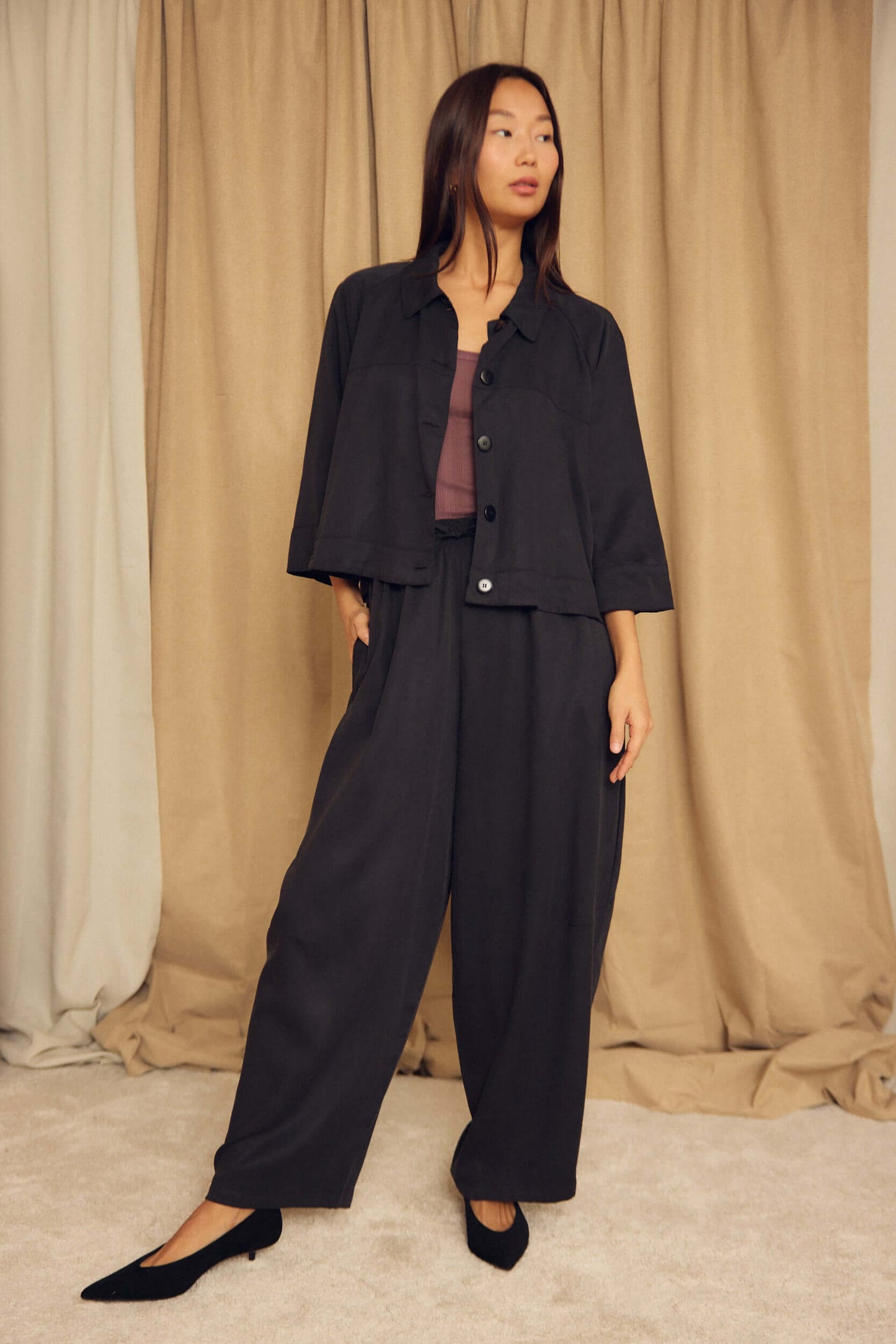 Model wearing Black Lyocell Barrel-Leg Trousers paired with a stylish cropped jacket on a soft background.