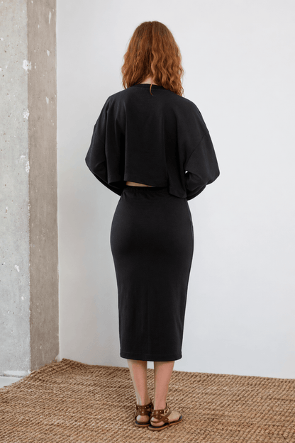 Organic Cotton Long Sleeve Top in Black worn from the back with a wide cropped silhouette and relaxed fit.