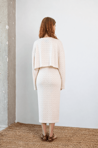 Model wearing Crochet Organic Cotton Midi Skirt in ecru from the back, showcasing its textured design and elegant silhouette.