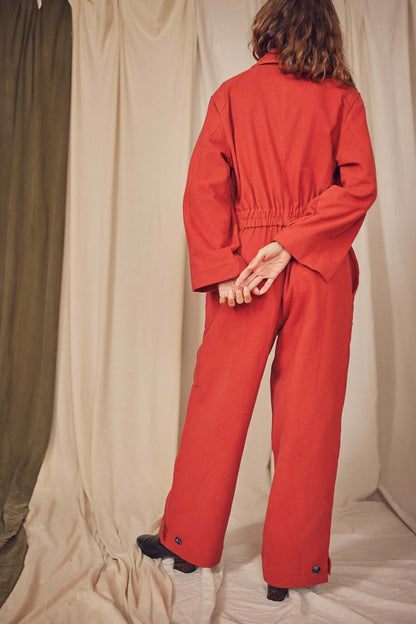 Model wearing a Rust Organic Cotton Boiler Suit, showcasing the back with a flattering waist detail and eco-friendly buttons.