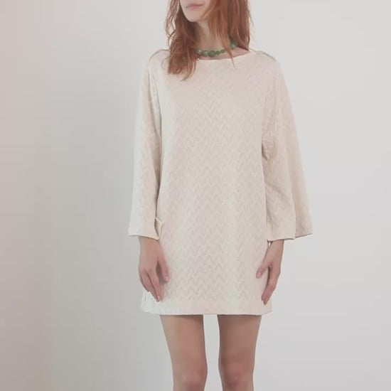 Model wearing an Organic Cotton Crochet Mini Dress with flared sleeves in ecru color.
