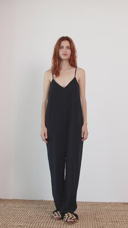 Model wearing Organic Cotton Wide Jumpsuit in Black, featuring a relaxed silhouette and slim straps.