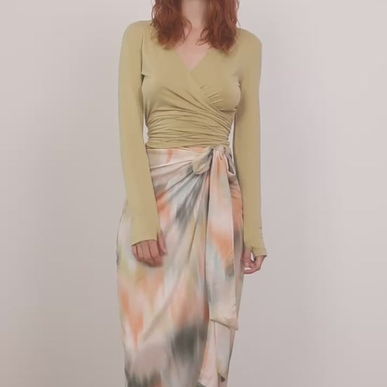Cupro Multiway Wrap Top in Soft Olive worn with a vibrant tie-dye skirt, showcasing versatile styling options.